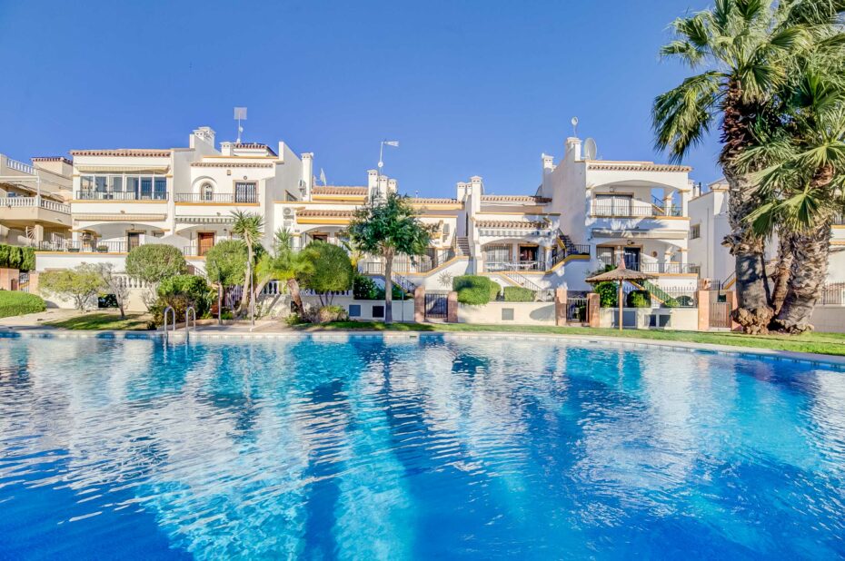 Ferieboliger i Los Dolses med udsigt til krystalklar swimmingpool og blå himmel.