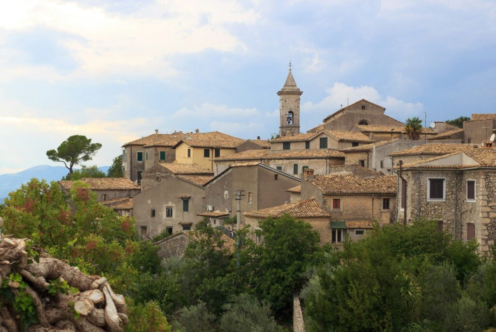 Tætte bygninger i Arpino omringet af natur og smuk blå himmel.